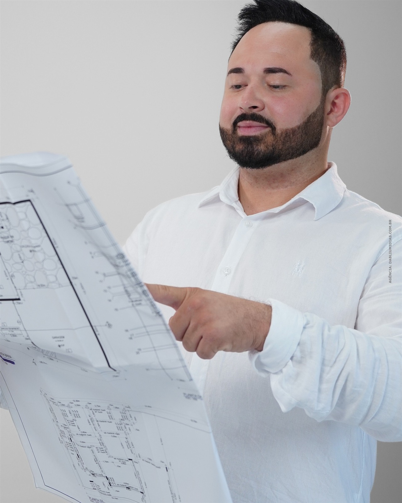 Arquiteto e urbanista Andrei Silva analisando uma planta baixa em ensaio de fotografia corporativa